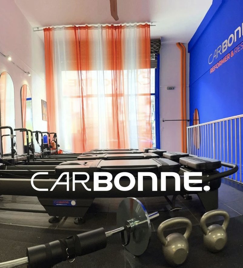Studio Carbonne : salle de reformer, mur bleu, rideaux orange